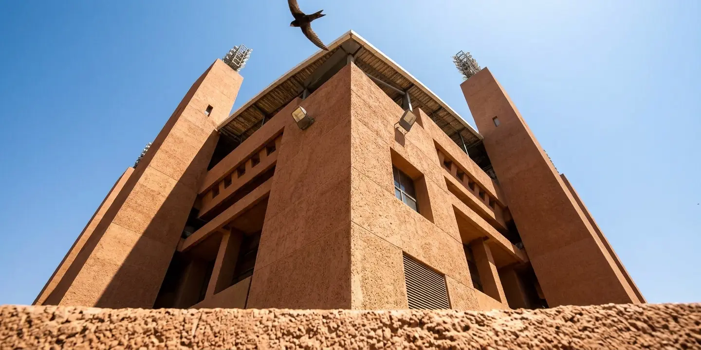 Grand Stade de Marrakech exterior by daylight, terracotta walls and corner towers on Marrakech's northern edge